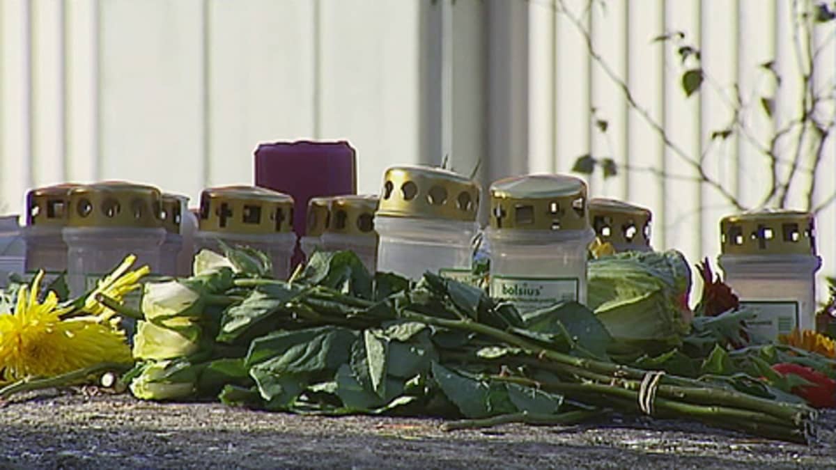 Kynttilöitä ja kukkia maassa.