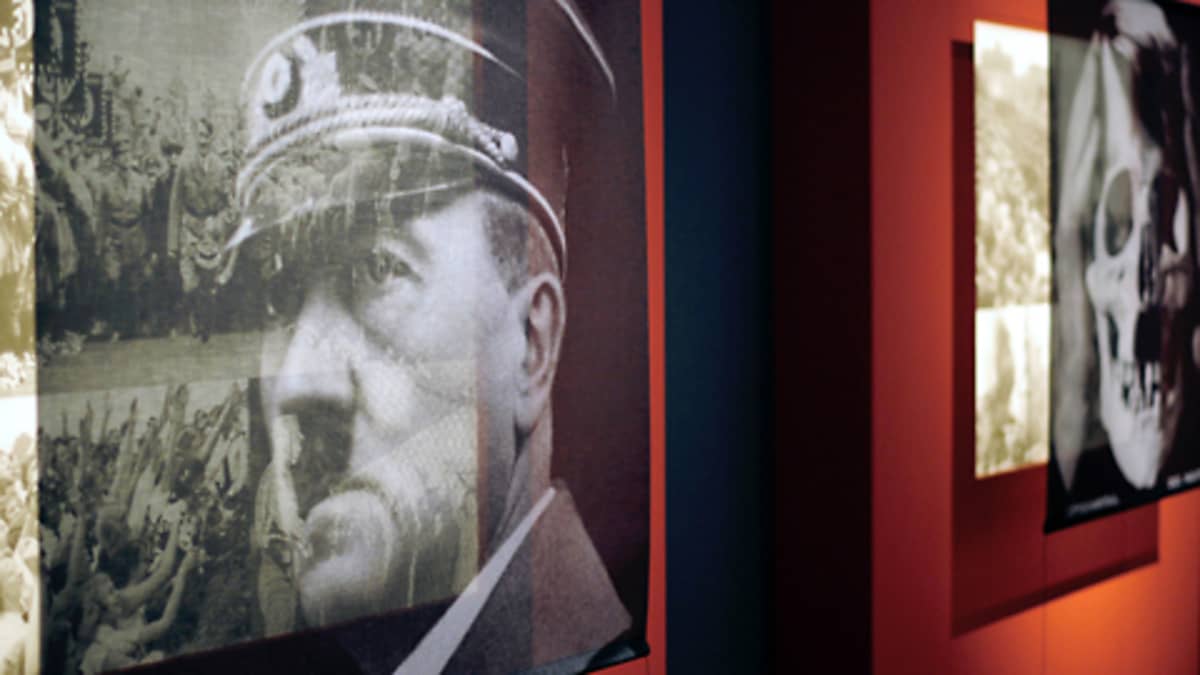Berliinin historiallisen museon näyttelystä otetussa valokuvassa muodostuu kaksoiskuvia näyttelyn etualalla ripustettujen, osittain läpinäkyvien valokuvien sekä niiden taustakuvien yhdistelmistä. Vasemmalla olevassa pääkuvassa Adolf Hitler, oikealla ihmisen pääkallo.