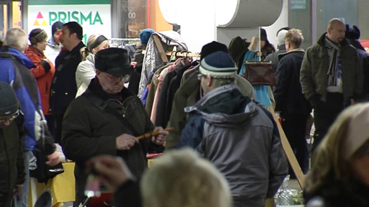 Ihmisiä tutkailemassa tavaroita kirpputorilla