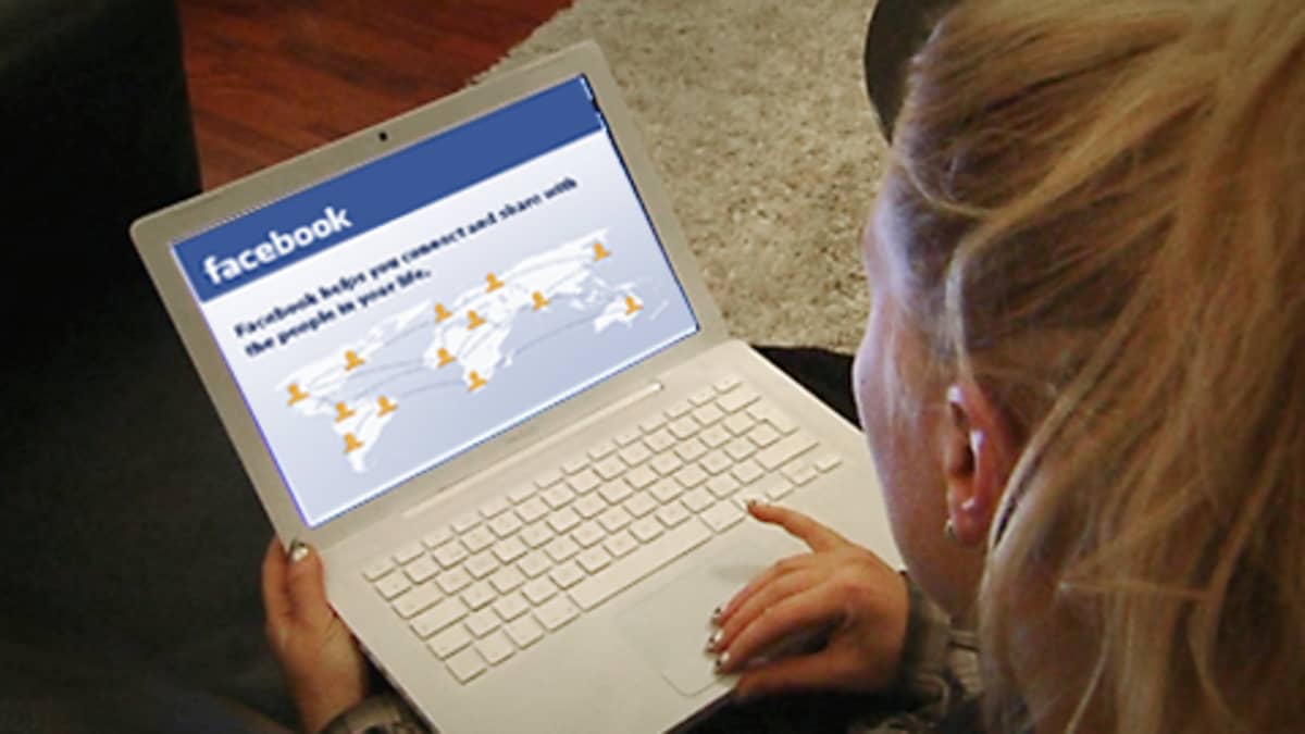 Henkilö kannettava tietokone sylissään, facebook-sivu avattuna