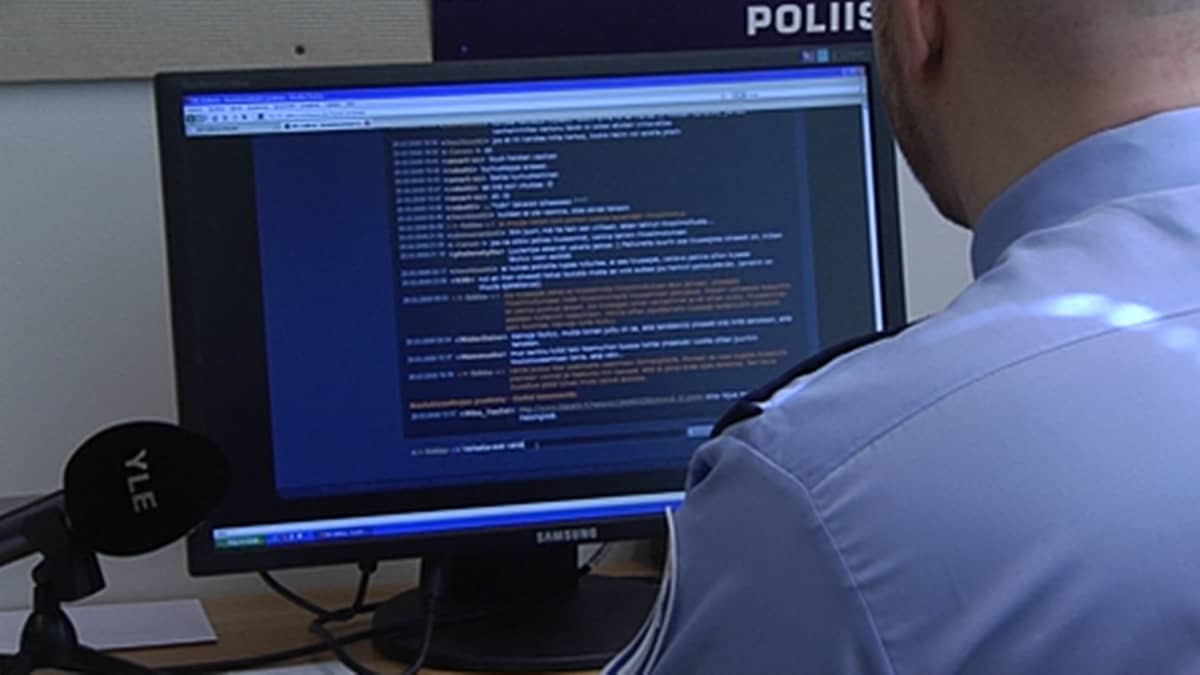 Poliisi istuu tietokoneen näytön äärellä virka-asussaan.