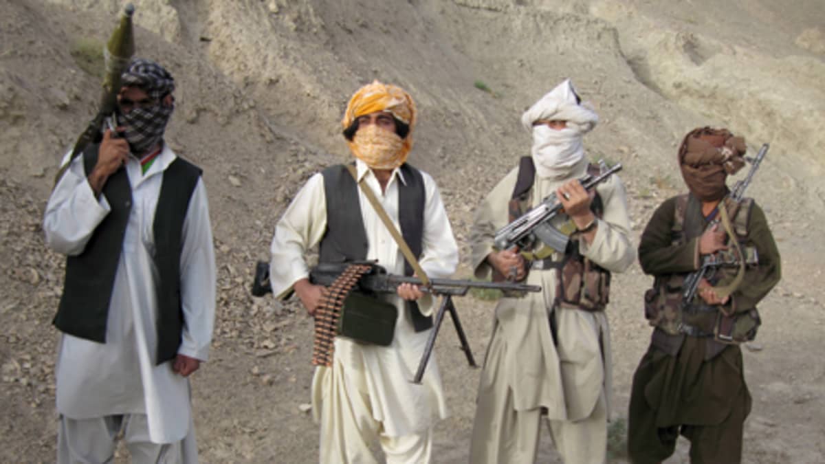 Neljä taliban-soturia kasvot osittain peitettyinä. Soturijoukolla on aseinaan sinko, konekivääri sekä kaksi rynnäkkökivääriä.