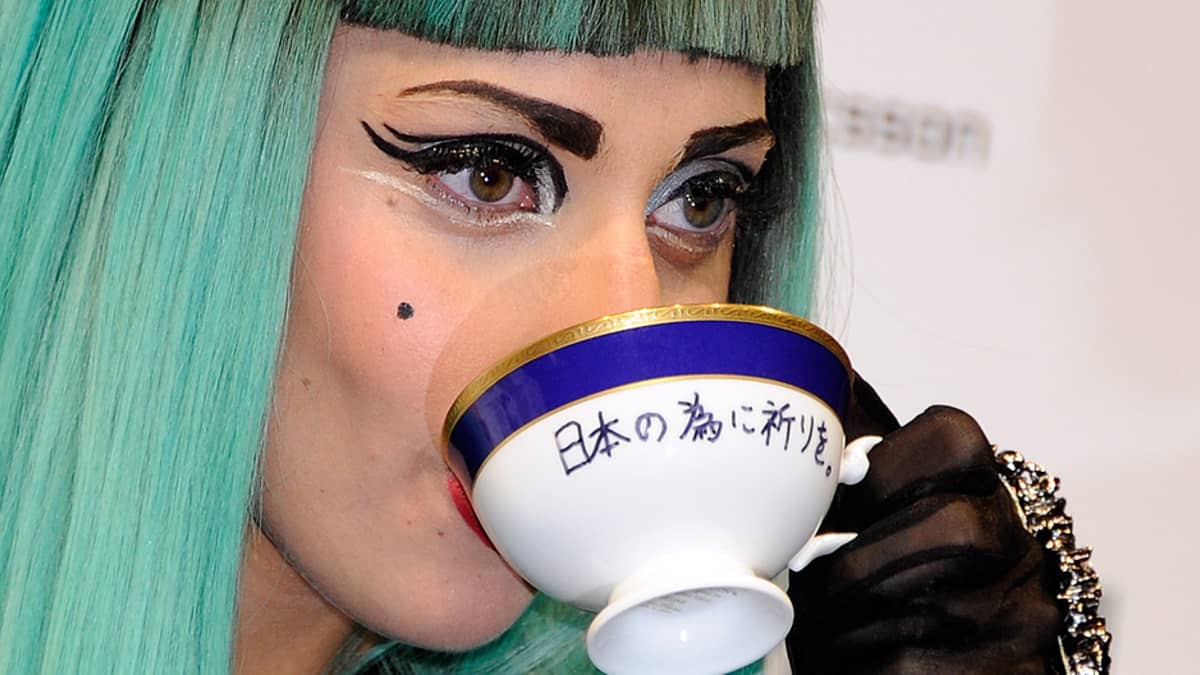 Lady Gaga juomassa huutokaupassa myydystä teekupista lehdistötilaisuudessa.