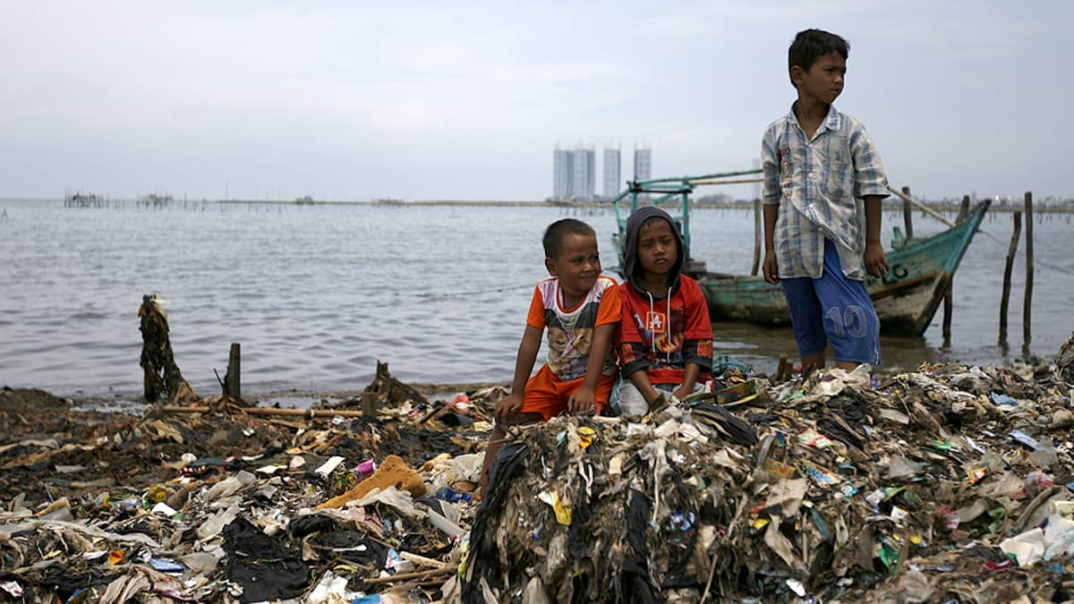 Pojat leikkivät jätteiden täyttämällä tekojärven rannalla.