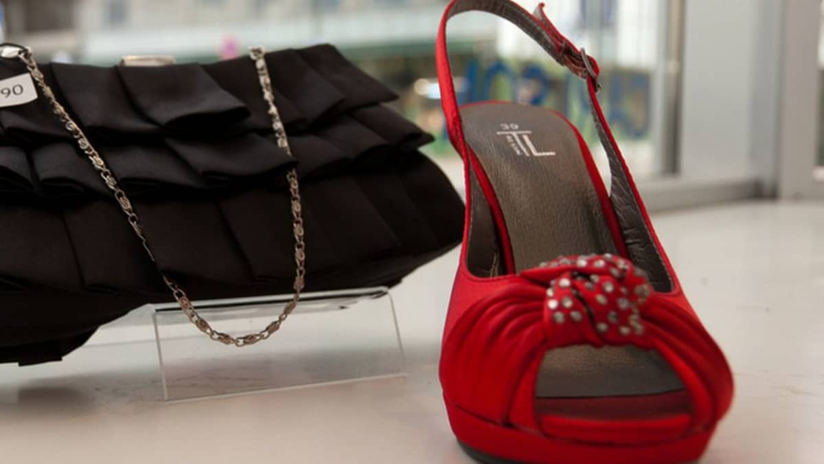 Musta käsilaukku ja punainen kenkä näyteikkunassa