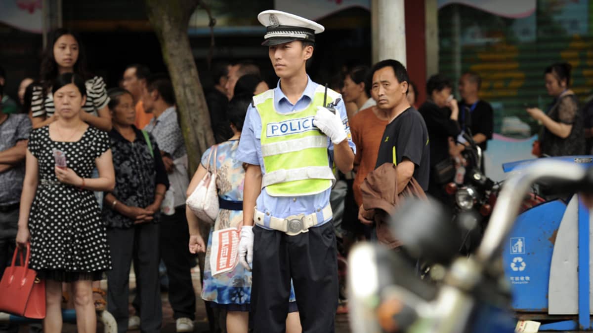 Poliisi valvoo ihmismassoja hallintorakennuksen edessä Shifangissa.