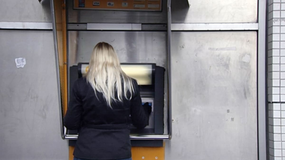 Nainen nostaa rahaa pankkiautomaatilla.
