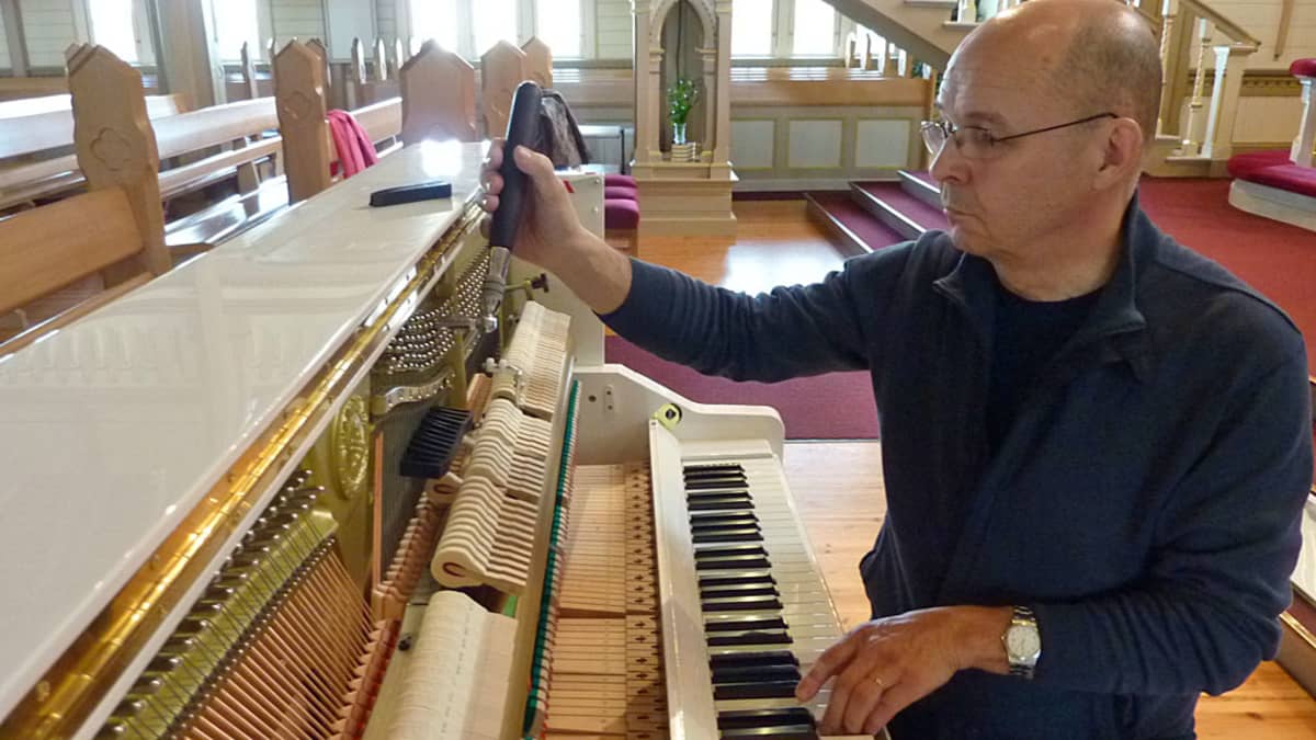 Hannu Aitoaho virittää pianoa Kajaanin kirkossa.