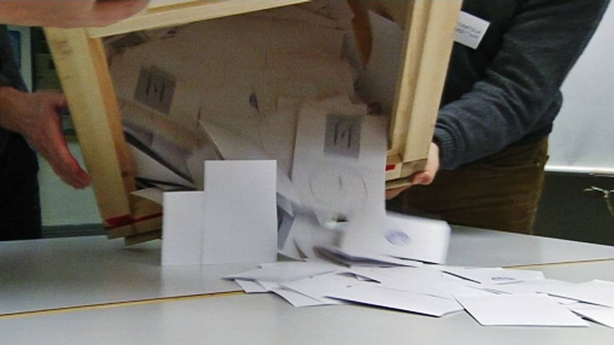 Virkailijat kaatavat äänestyslipukkeita vaaliuurnasta pöydälle.
