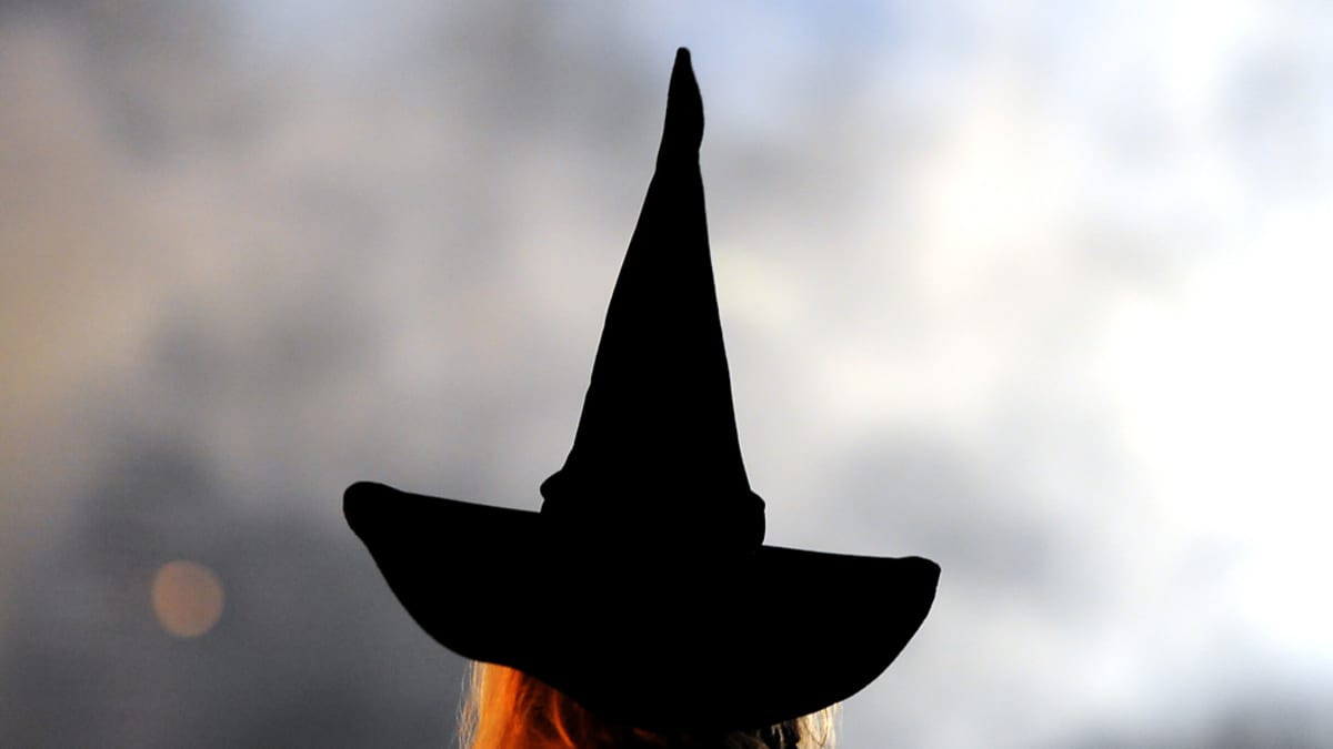 Musta, korkea, noitamainen hattu kuvattuna vaaleaa taustaa vasten.