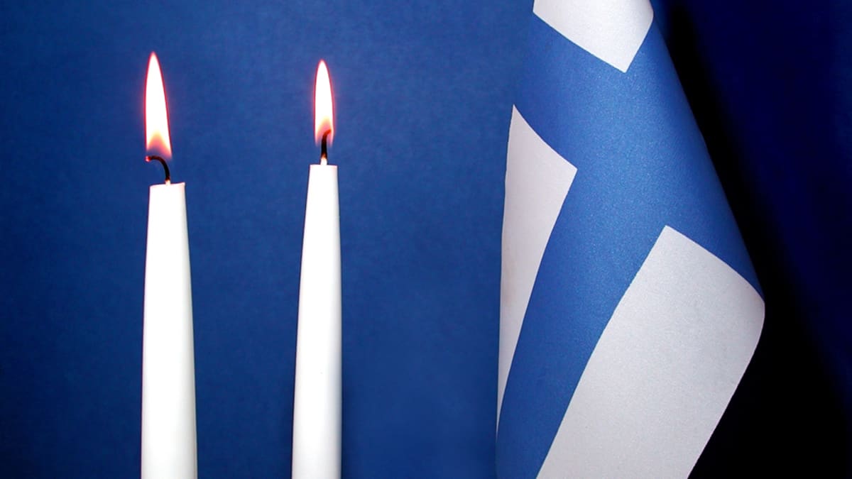 Kaksi kynttilää ja Suomen lippu.