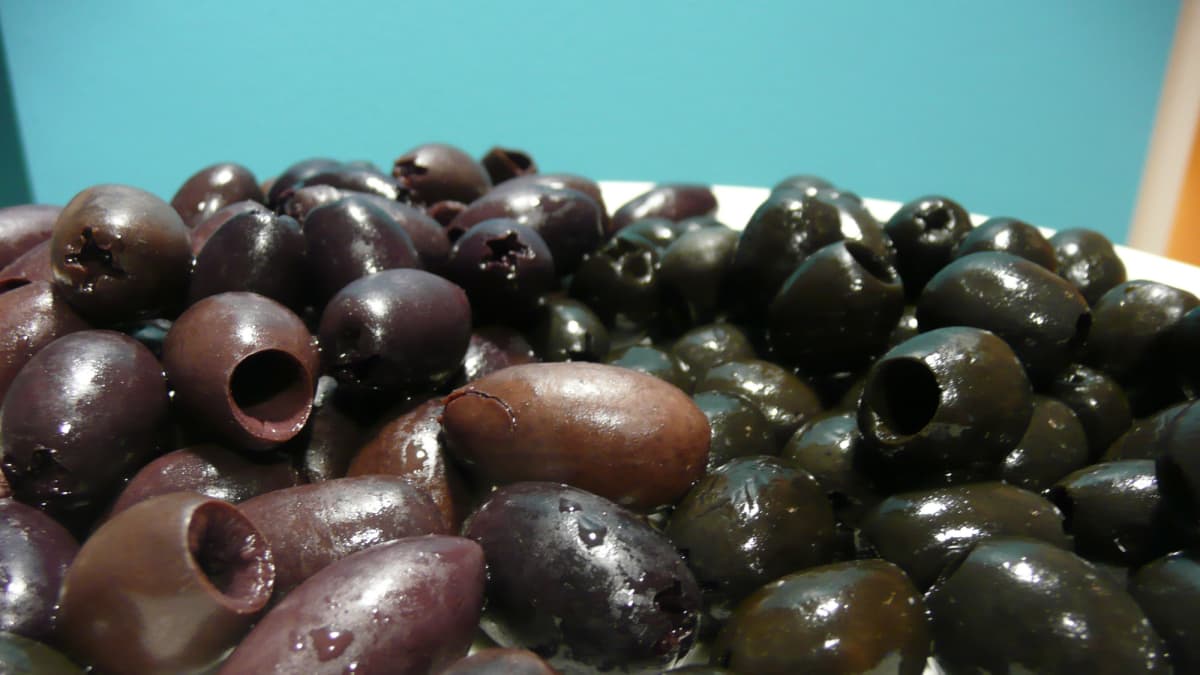 Lautasella kalamata-oliiveja ja mustia oliiveja.