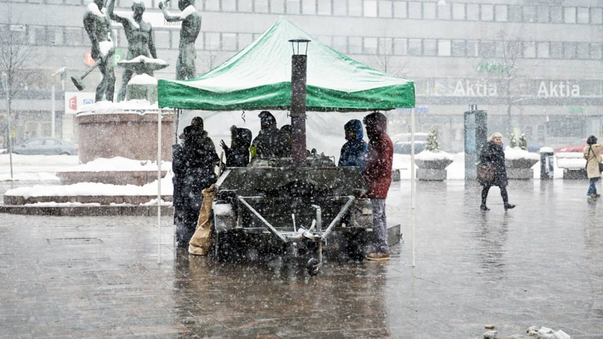 Ihmisä lumisateessa Helsingin Kolmensepänaukiolla helmikuussa.