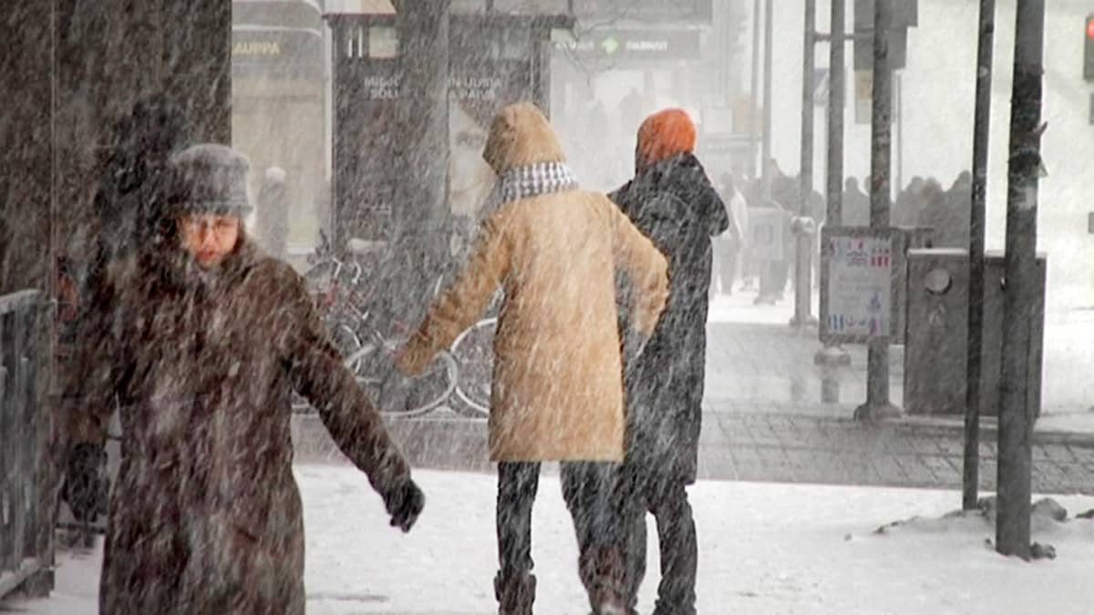 Ihmiset kävelevät lumipyryssä Turussa.