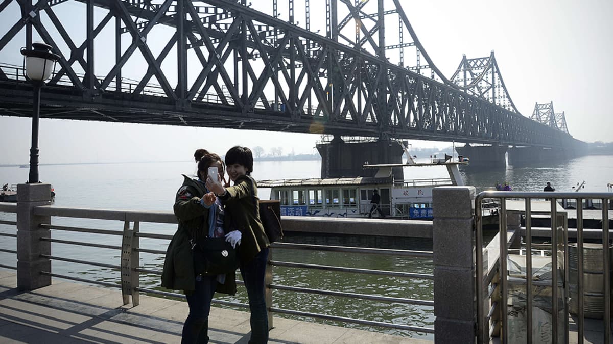 Kaksi kiinalaisnaista kuvaa itseään Yalujoen ylittävän sillan vierellä.
