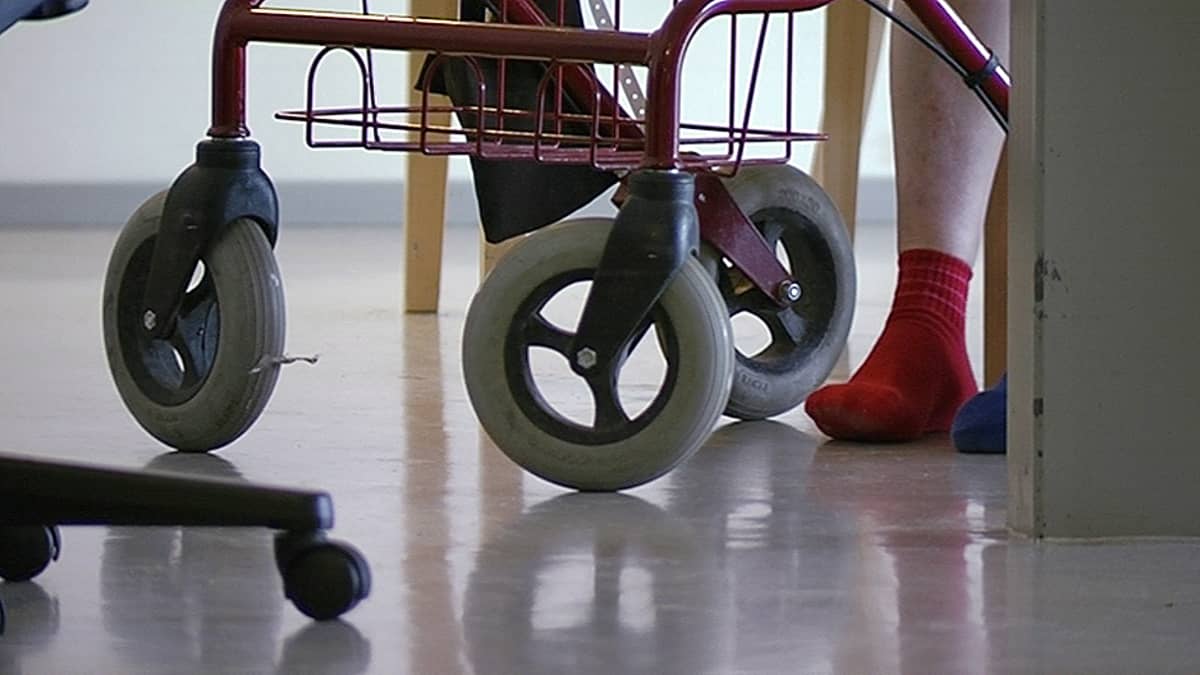Henkilön jalat rollaattorin vierellä.