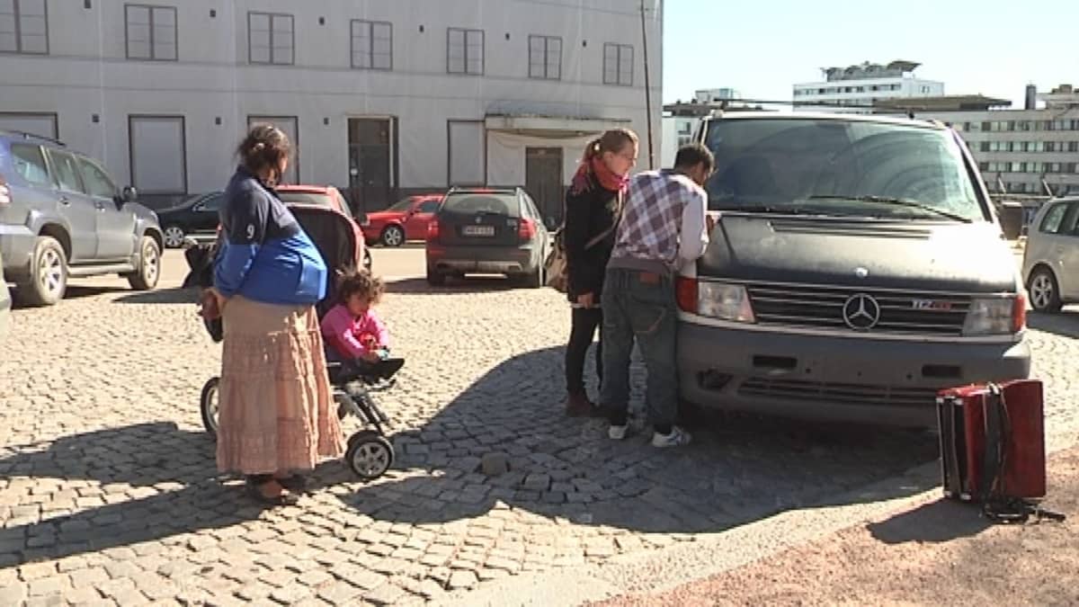 Romanikerjäläisperhe pakettiautonsa vieressä.