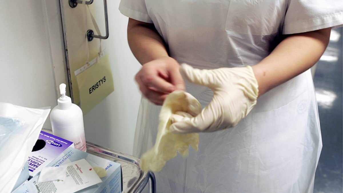 Sairaanhoitaja laittaa kumihanskaa käteensä Meilahden sairaalassa.