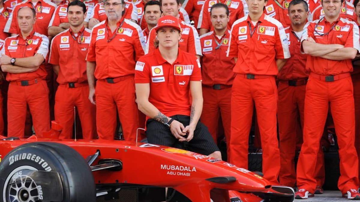 Kimi Räikkönen poseeraa Ferrari-auton ja tallin henkilökunnan kanssa.