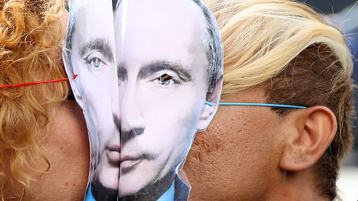 Kaksi ihmistä suutelee toisiaan Putinin pahvinaamarit kasvoillaan. Kuva on mielenosoituksesta Pariisista 8. syyskuuta 2013.