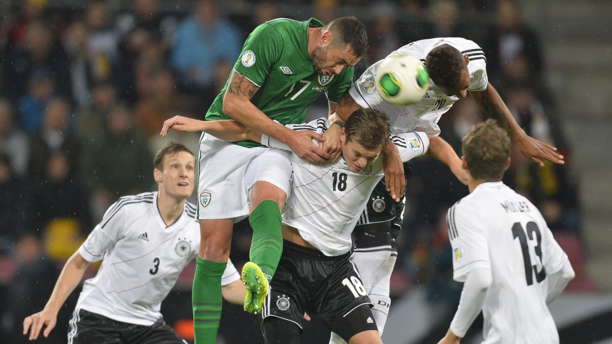 Irlannin Damien Delaney taistelee pääpallosta yhdessä Saksan Toni Kroosin ja Jerome Boatengin kanssa.