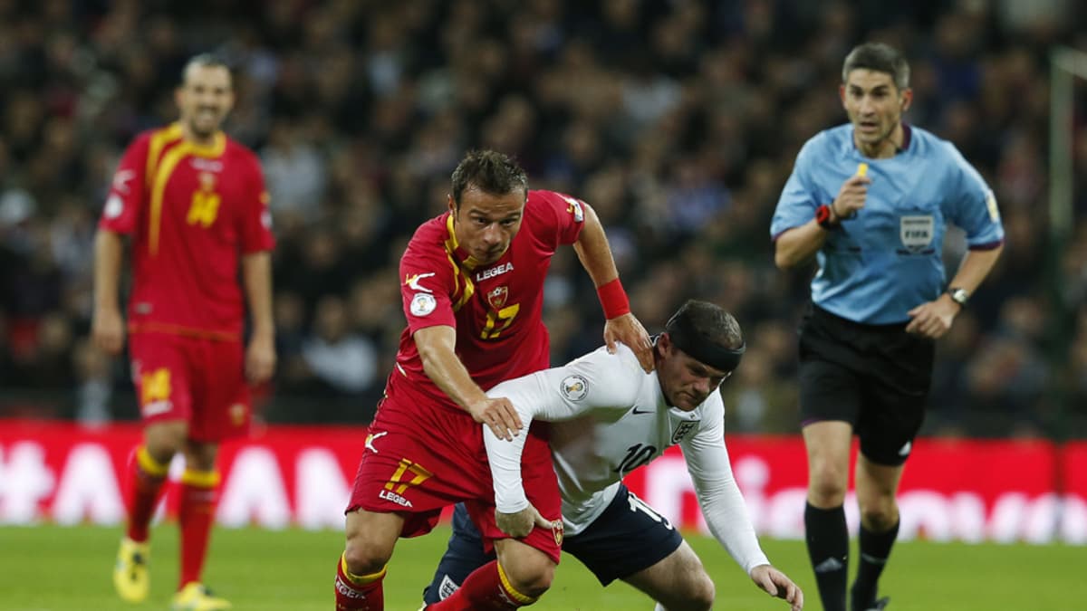 Montenegron Elsad Zverotic (vas.) ja Englannin Wayne Rooney (oik.) kamppailevat pallosta.