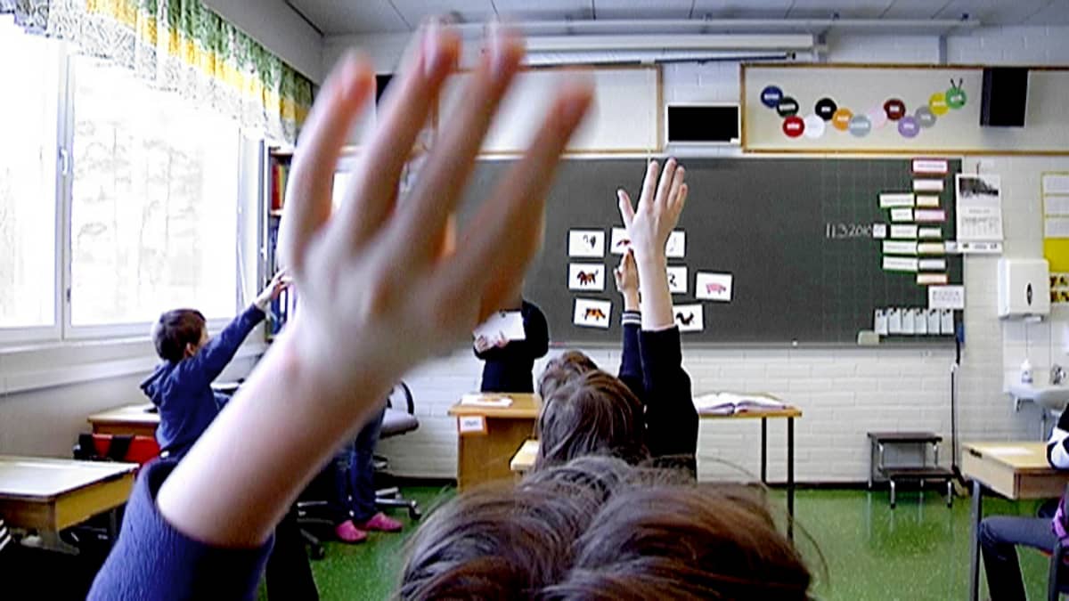 Lapset viittaavat oppitunnilla alakoulussa. 