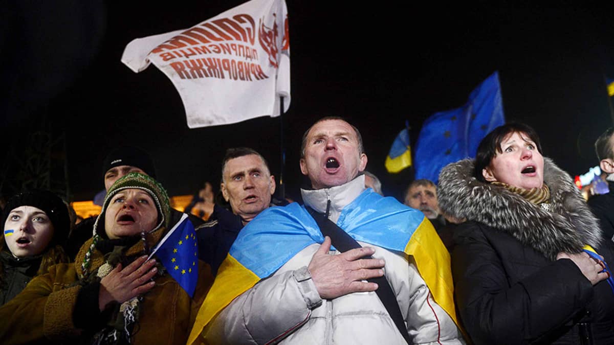Ihmiset laulavat Ukrainan kansallislaulua Kiovassa osana mielenosoitusta.