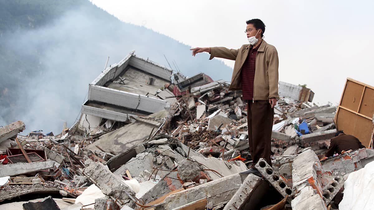 Kiinalainen mies osoittaa paikkaa pahoin maanjäristyksen runtelemalla alueella Kiinan Sichuanissa.