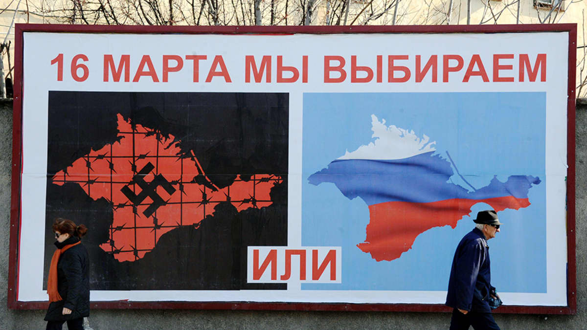 Ihmisiä kadulla Sevastopolissa 11. maaliskuuta 2014 - mainoksessa lukee: "16. maaliskuuta valitsemme joko... tai...".