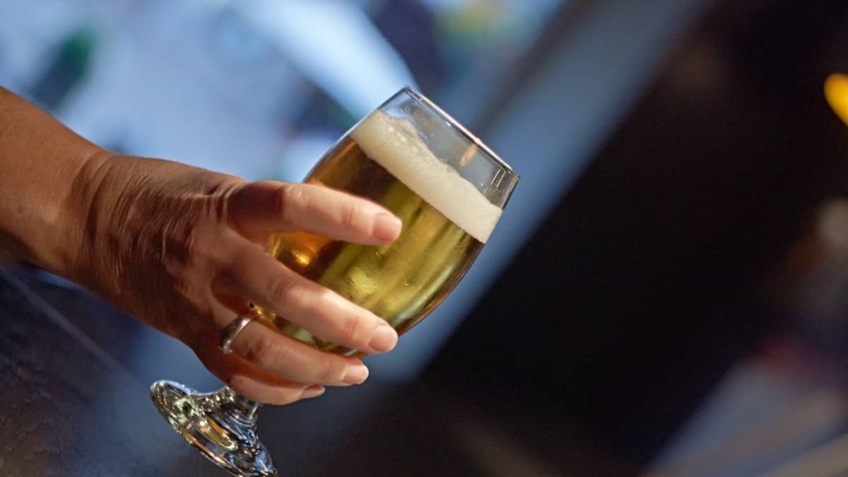 Glass of beer held in a woman's hand.