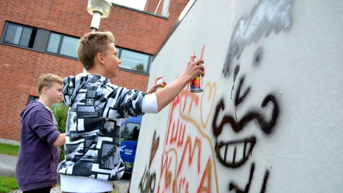 Nuoret pojat maalaamassa graffiteja