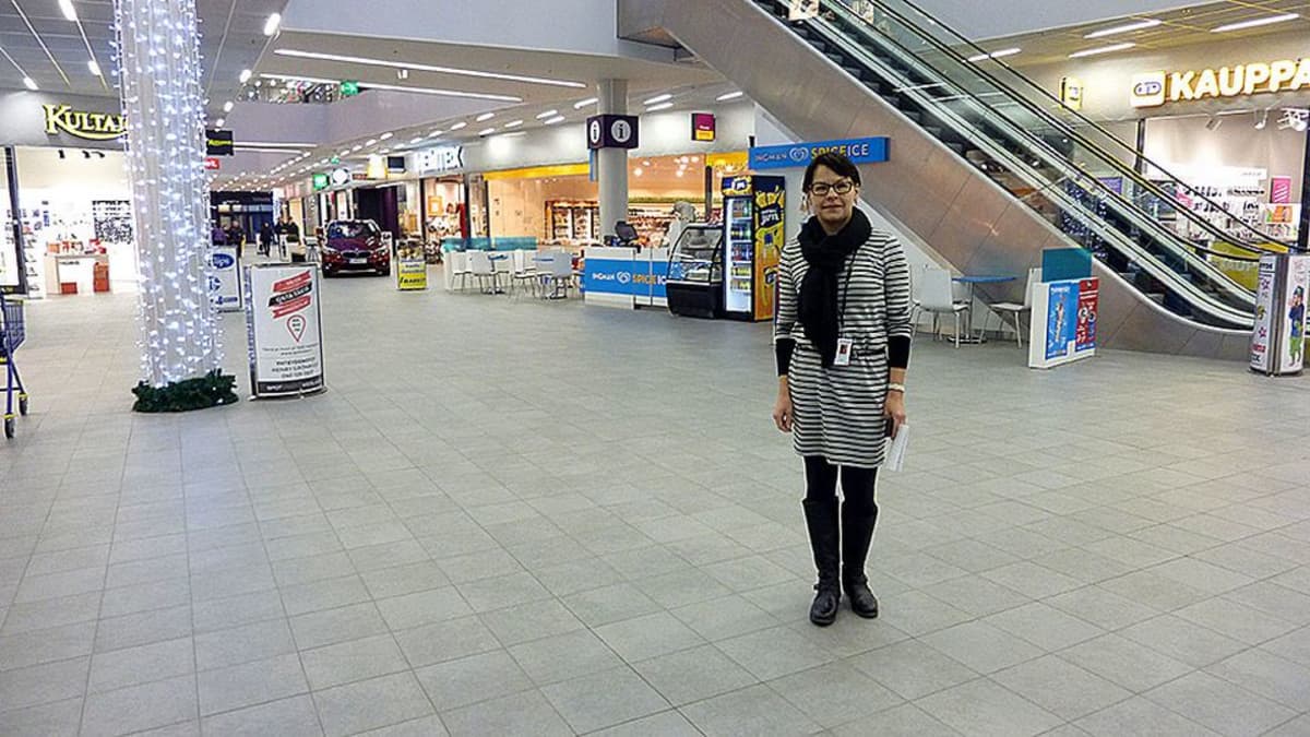 Nainen seisoo kauppakeskuksen aulassa.