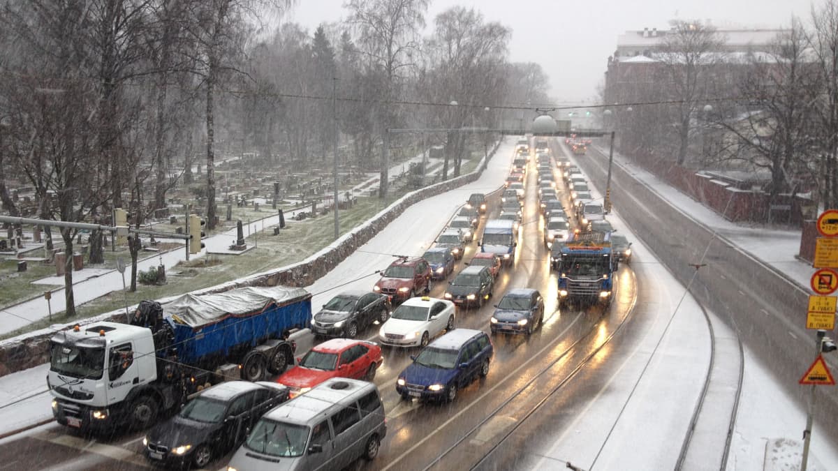 Lunta sataa Helsingissä, autot seisovat ruuhkassa