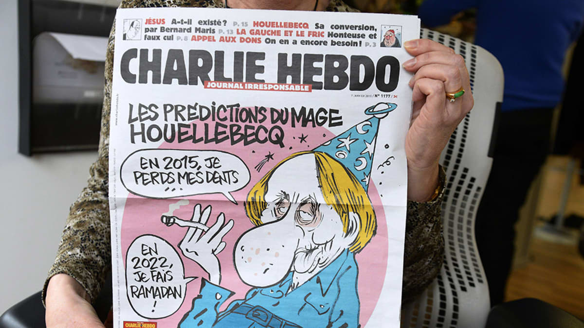 Henkilö näyttää ranskalaisen satiirisen sanomalehden Charlie Hebdon etusivua.