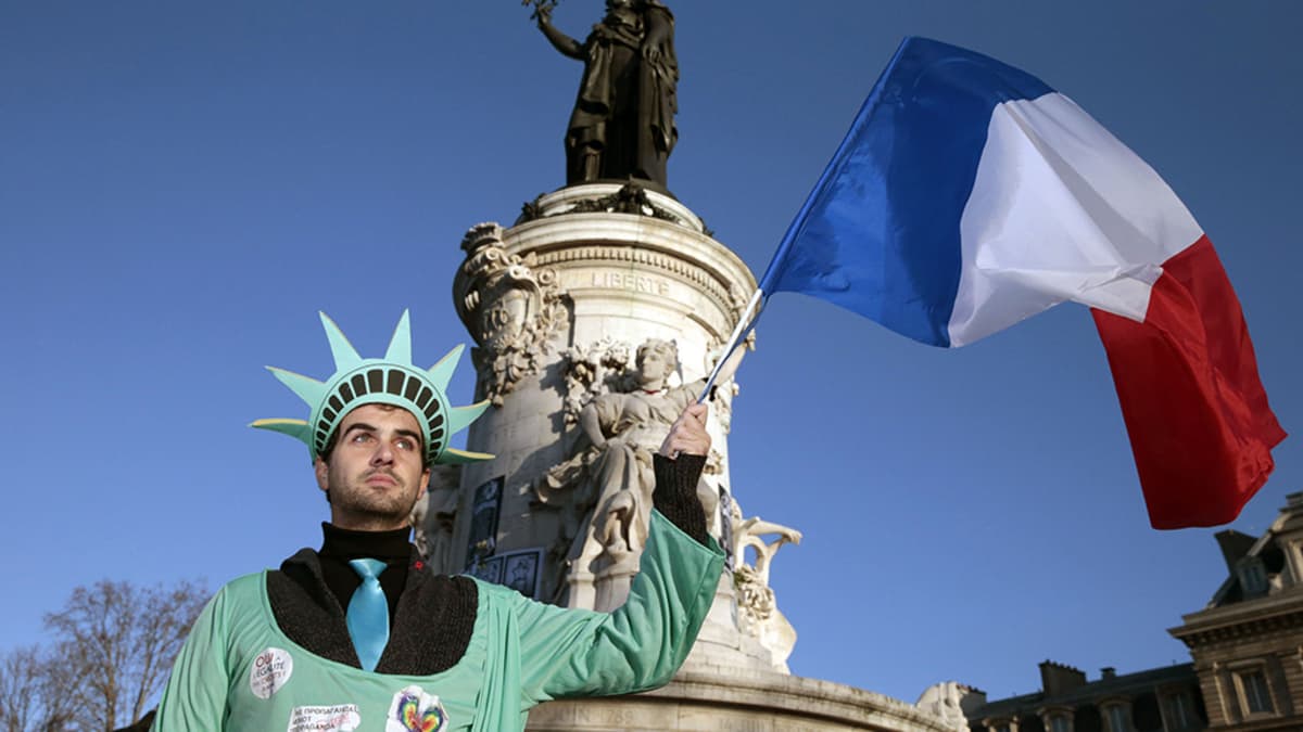 Vapaudenpatsaaksi pukeutunut mies piteli ranskan lippua Place de la Republiquella sunnuntaina.