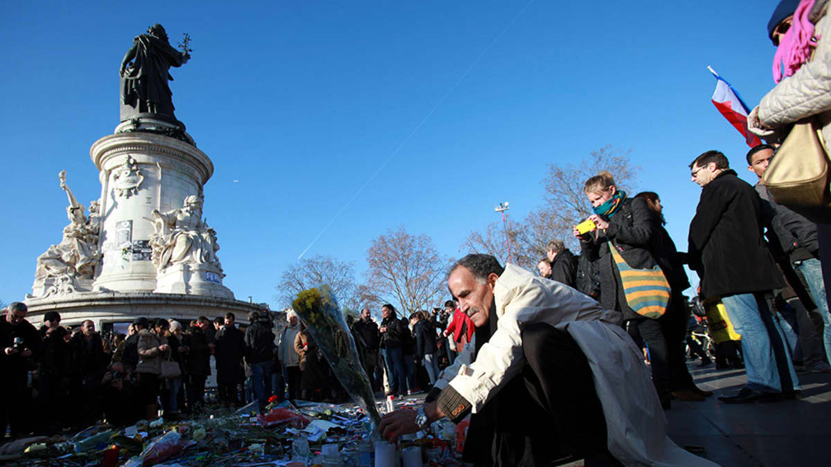Mies toi kukkia terrori-iskuissa kuolleiden muistolle Pariisissa sunnuntaina.