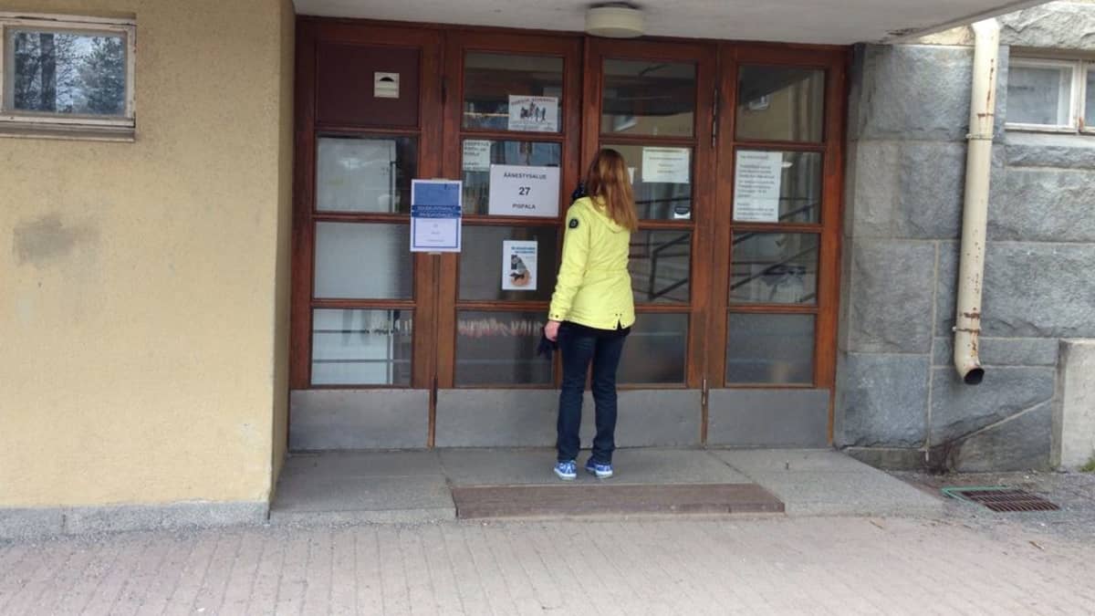Nuori nainen avaamassa Pispalan koulun ovea.
