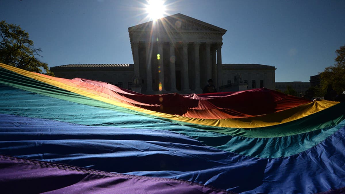 Homoliittojen kannattajat pitelivät sateenkaarilippua Yhdysvaltain korkeimman oikeuden edessä Washingtonissa 28. huhtikuuta.