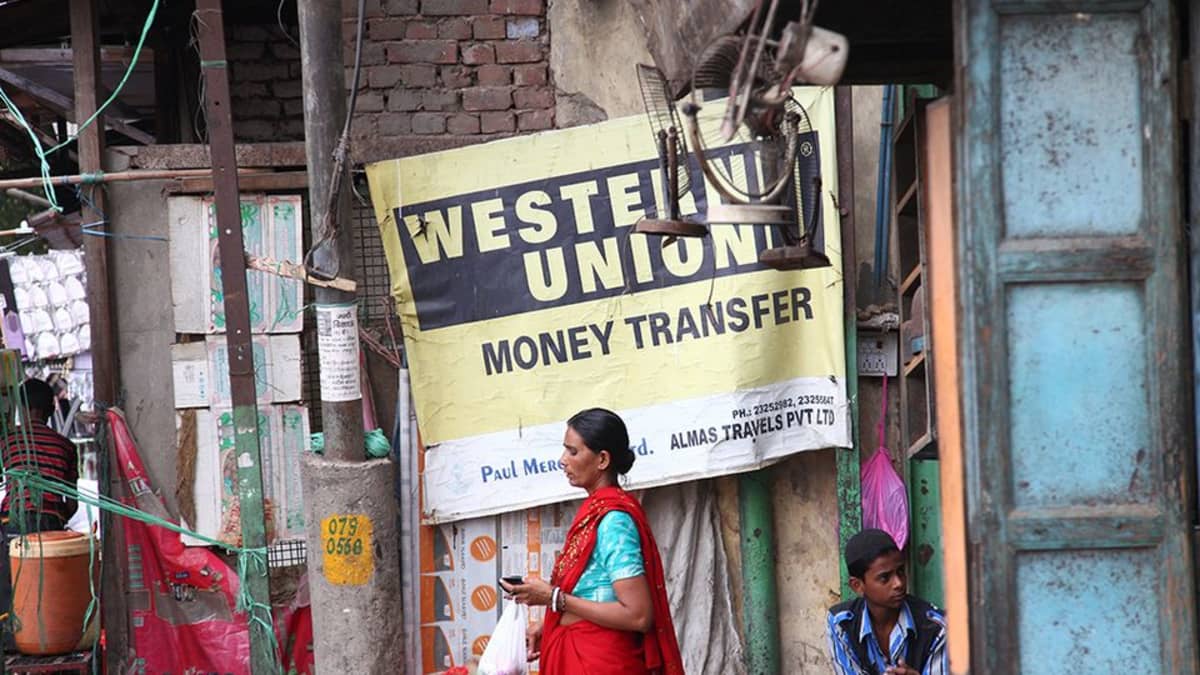 Nainen Western Unionin mainoksen edessä Intiassa.