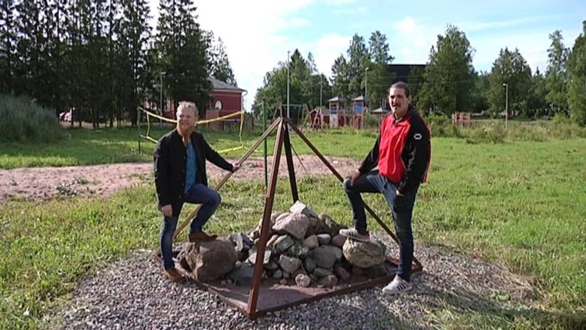 Pyramidipiknikin järjestäjät kivistä kootun pyramidin vieressä.