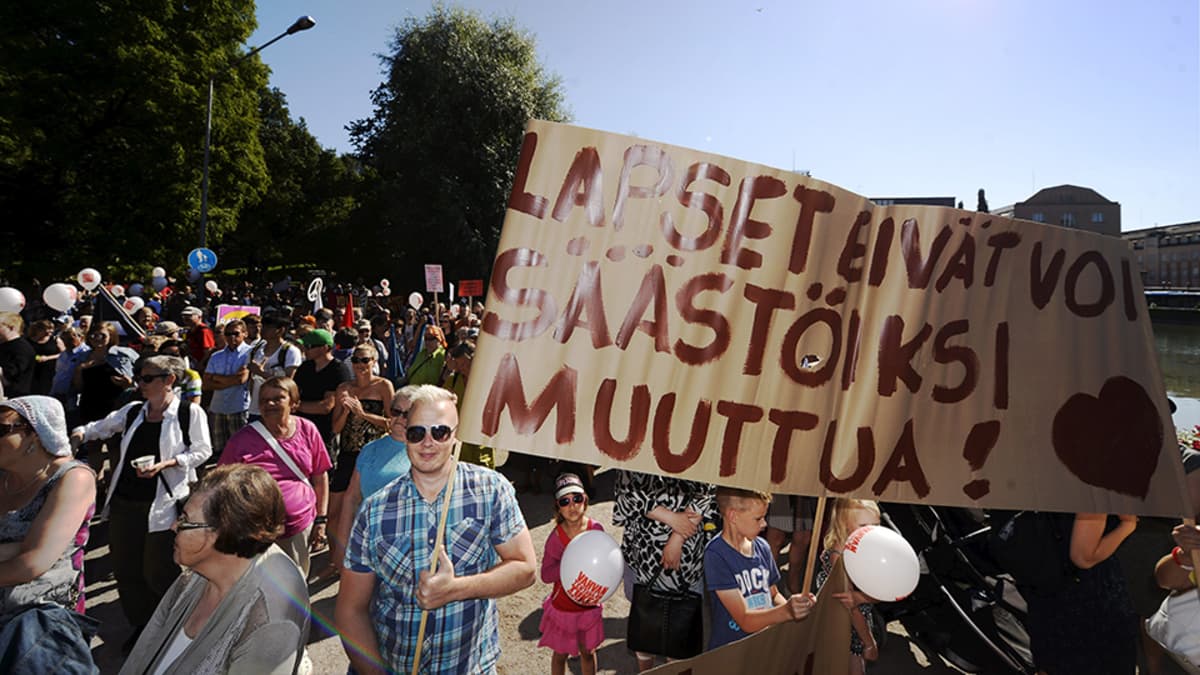  Lapsia puolustava kyltti mielenosoituksessa hallituksen leikkauksia ja "kurjistamispolitiikkaa" vastaan Helsingissä 22. elokuuta.