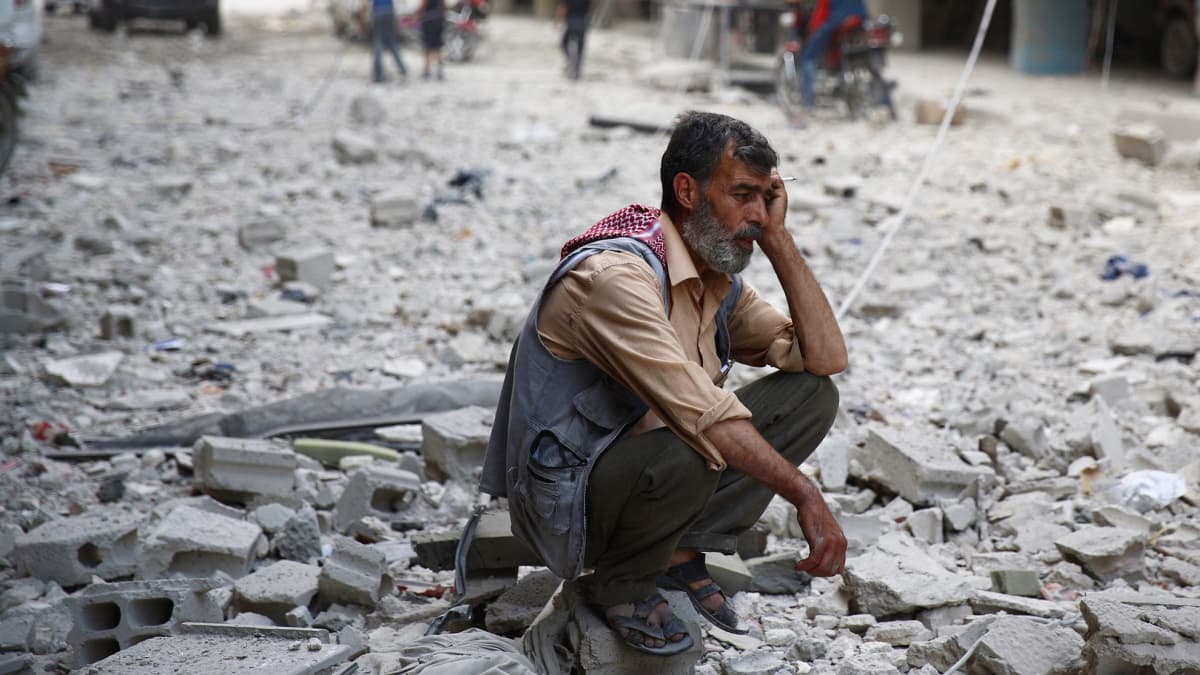 Syyrialaismies istuu Douman kaupungin raunioissa hallituksen joukkojen tekemän ilmaiskun jälkeen. Kuva on otettu 30. elokuuta. Jopa 240 000 ihmisen arvioidaan kuolleen Syyrian sodassa.
