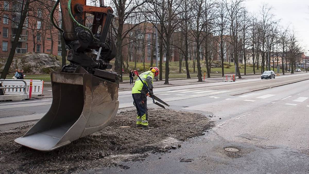 Kaivinkoneen kauha ja lapiomies.