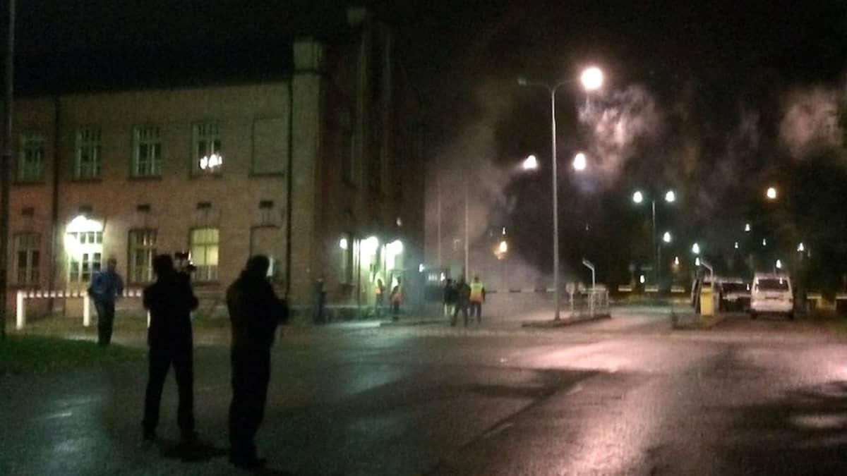 Poliiseja ja mielenosoittajia Hennalan entisen kasarmialueen portilla.