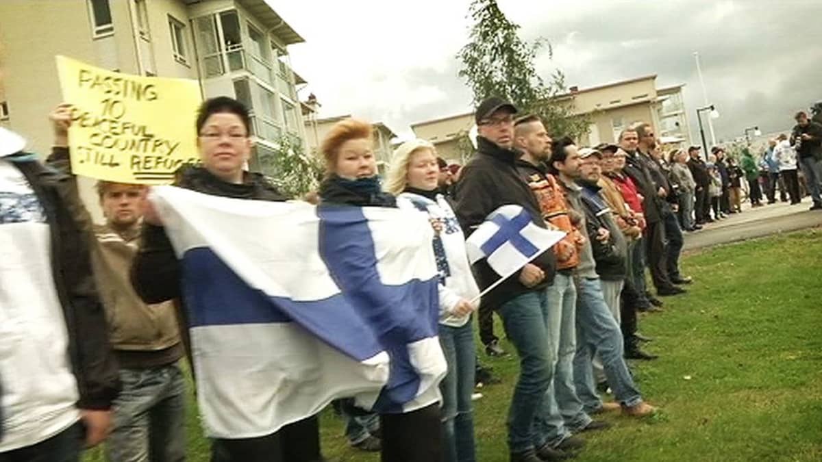 Mielenosoittajia Suomen lippujen kanssa.
