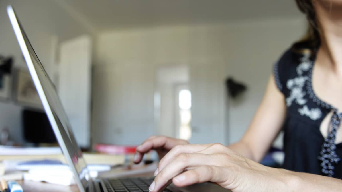 Nainen kirjoittaa kannettavalla tietokoneella.