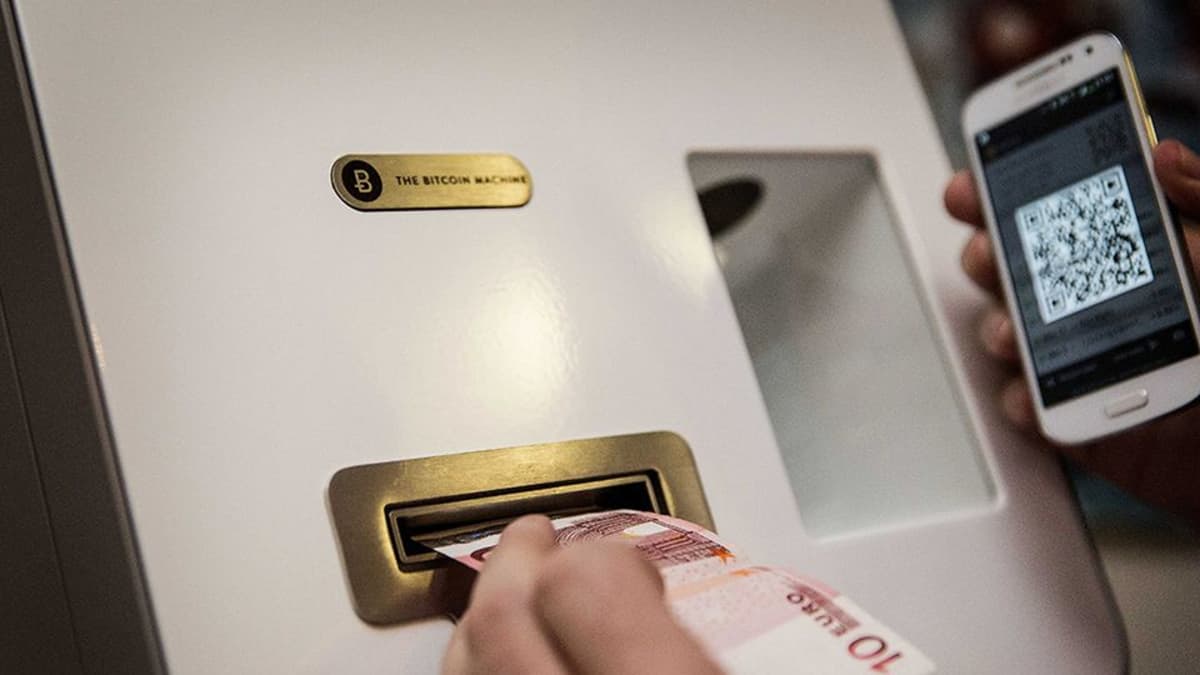 Asiaks vaihtaa käteistä rahaa digirahaksi  bitcoinautomaatilla.
