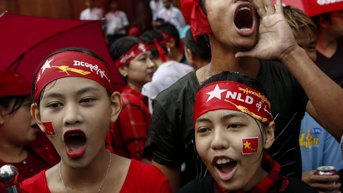 Kolme NLD-puolueen punaisiin päänauhoihin sonnustautunutta nuorta huutaa suureen ääneen. 