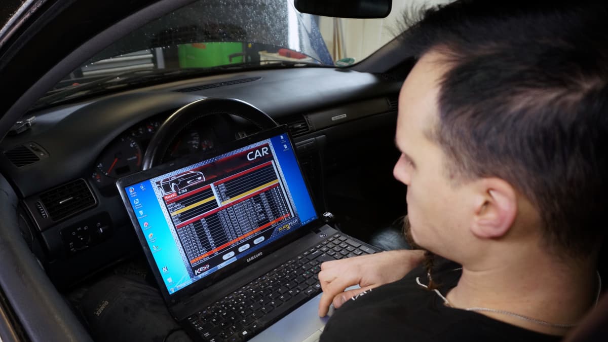 Autoasentaja käy auton ohjelmistoa läpi tietokoneella.